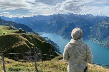 Donna di spalle ammira vista panoramica sulle Alpi svizzere con lago cristallino e montagne imponenti