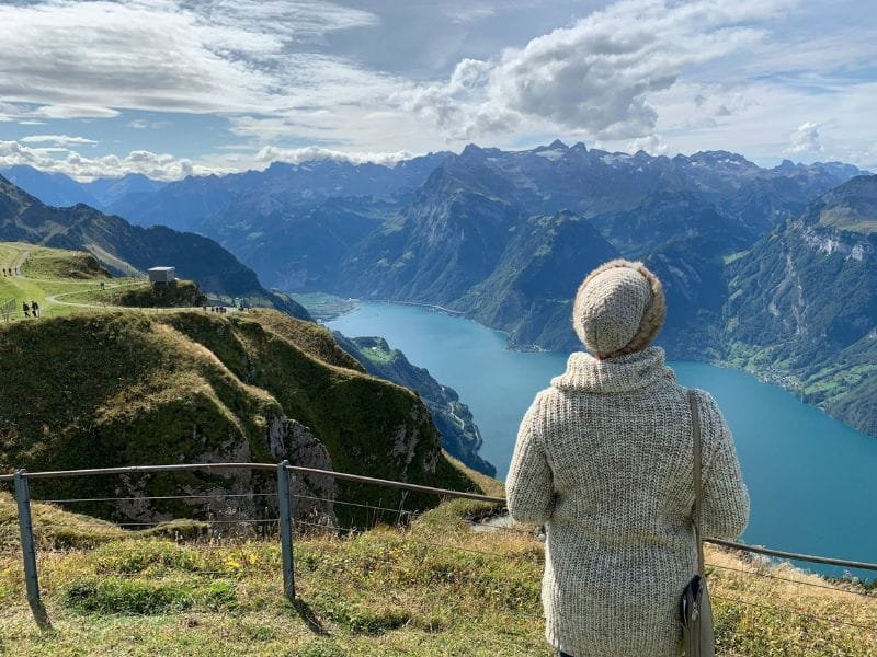 Donna di spalle ammira vista panoramica sulle Alpi svizzere con lago cristallino e montagne imponenti