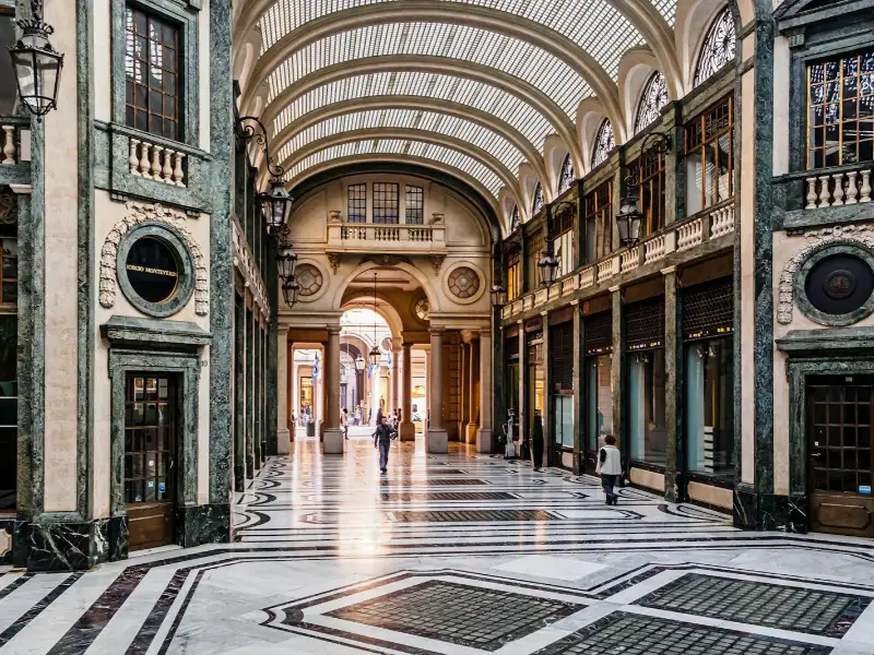Interno della Galleria Subalpina a Torino, con eleganti portici, pavimento decorato e copertura in vetro.